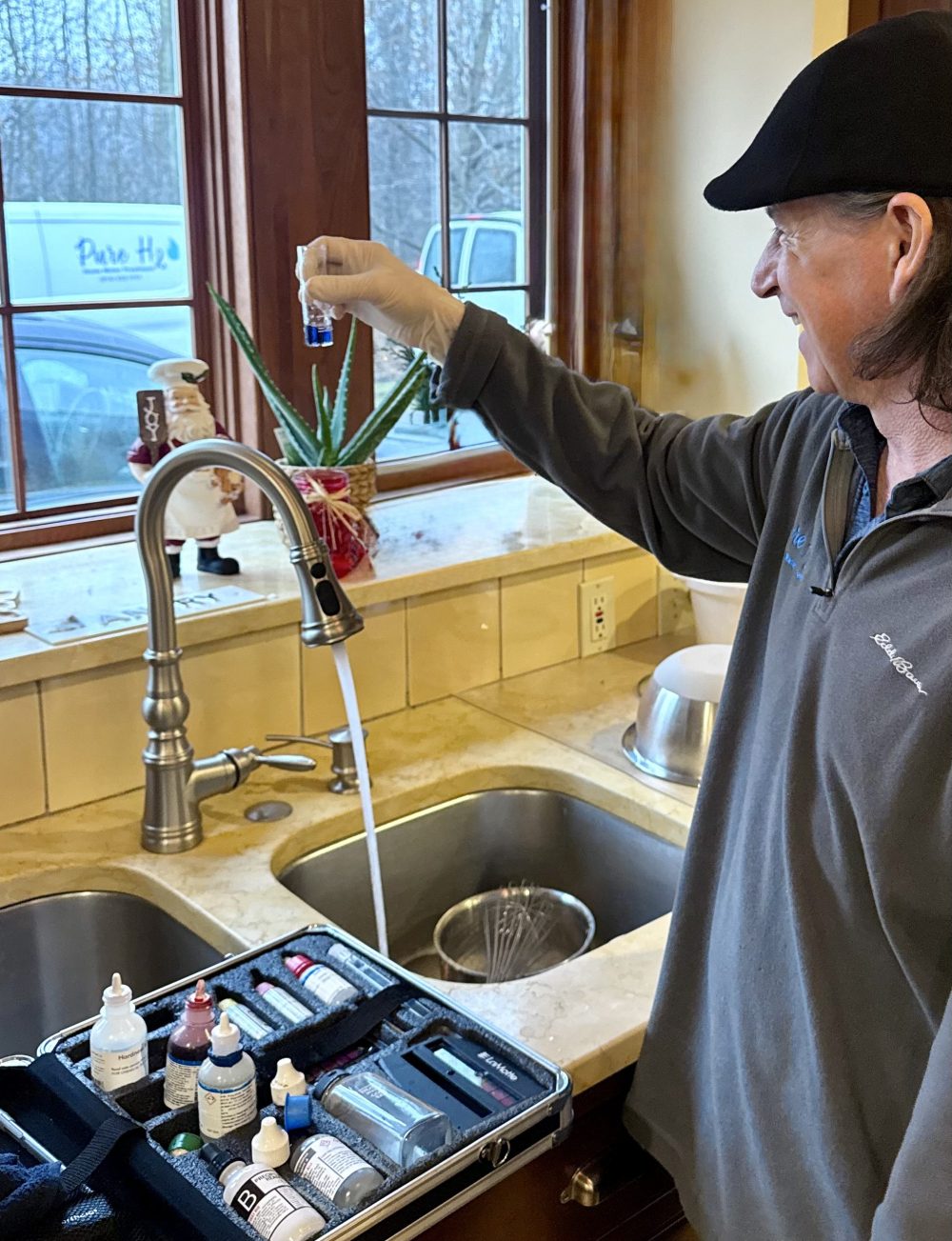 Pure H2O technician performing an in-home water test at a customer's kitchen sink